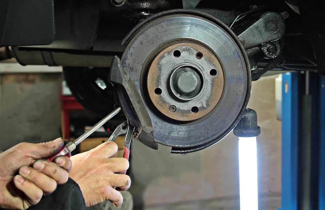 Mechanic repairing a car's front brake disc and caliper in a repair shop
