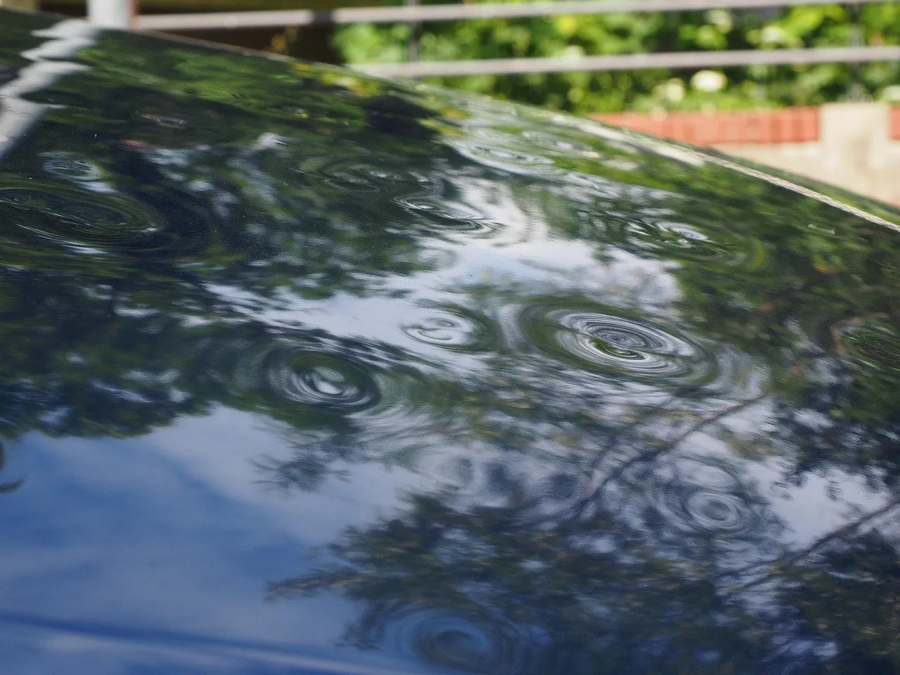 Dents from hail damage on the roof of a dark blue car