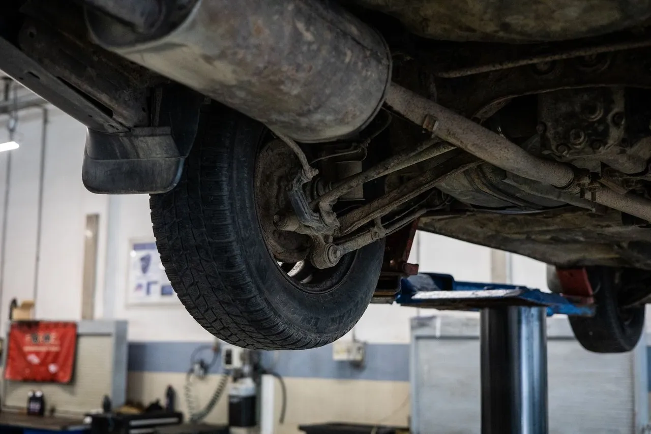 Underside of a used car raised on a lift for a mechanical inspection