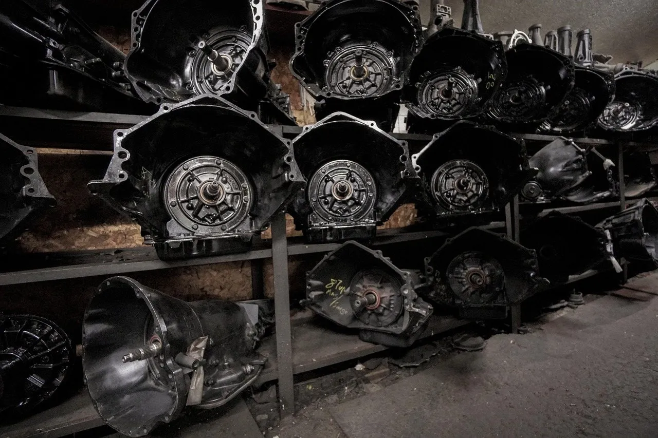 Rows of car transmissions stacked on metal shelves in a repair shop