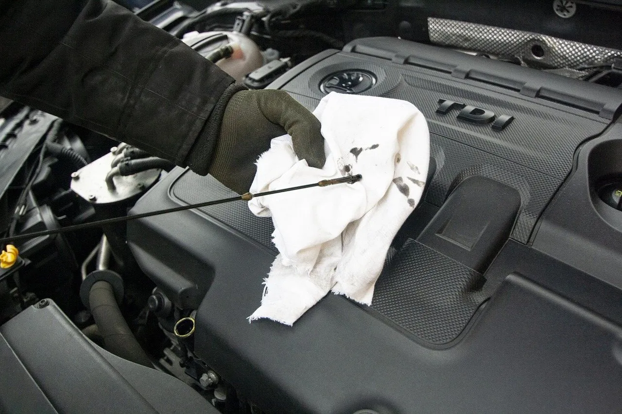 Mechanic wiping an engine oil dipstick during a scheduled service